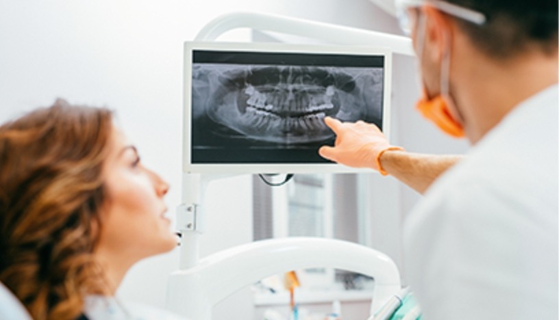 Oral surgeon and patient looking at digital x-rays